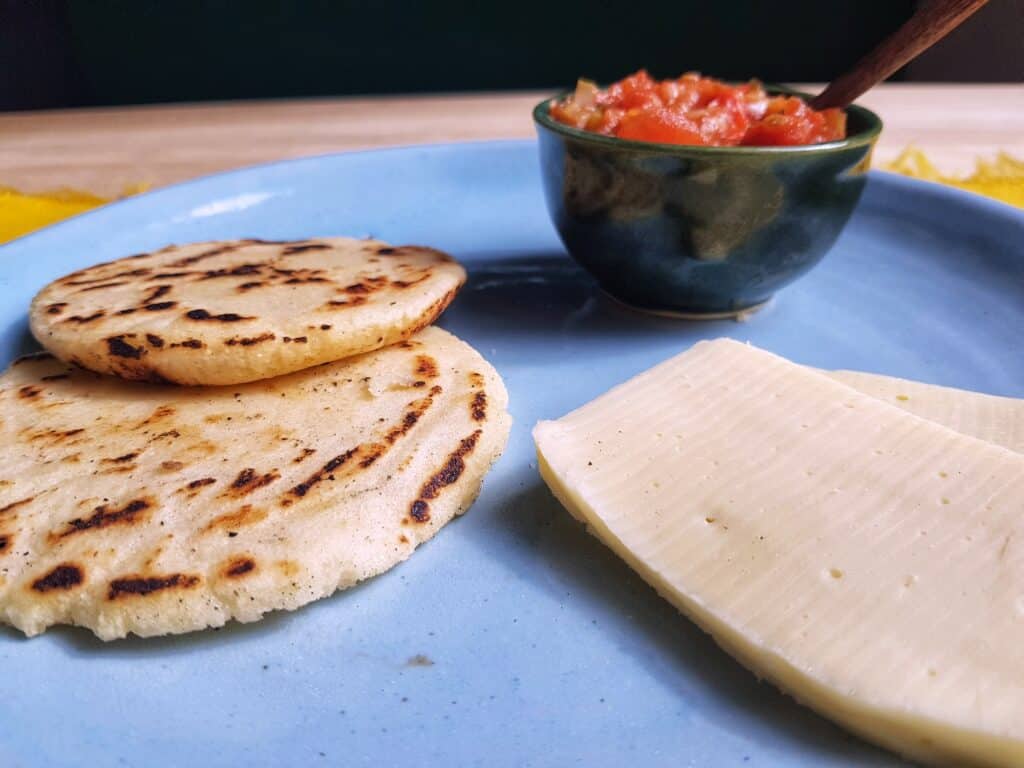 2 arepas with cheese and hogao on a blue plate