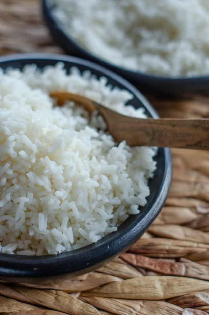 bol negro con arroz blanco suelto y una cucharada de madera