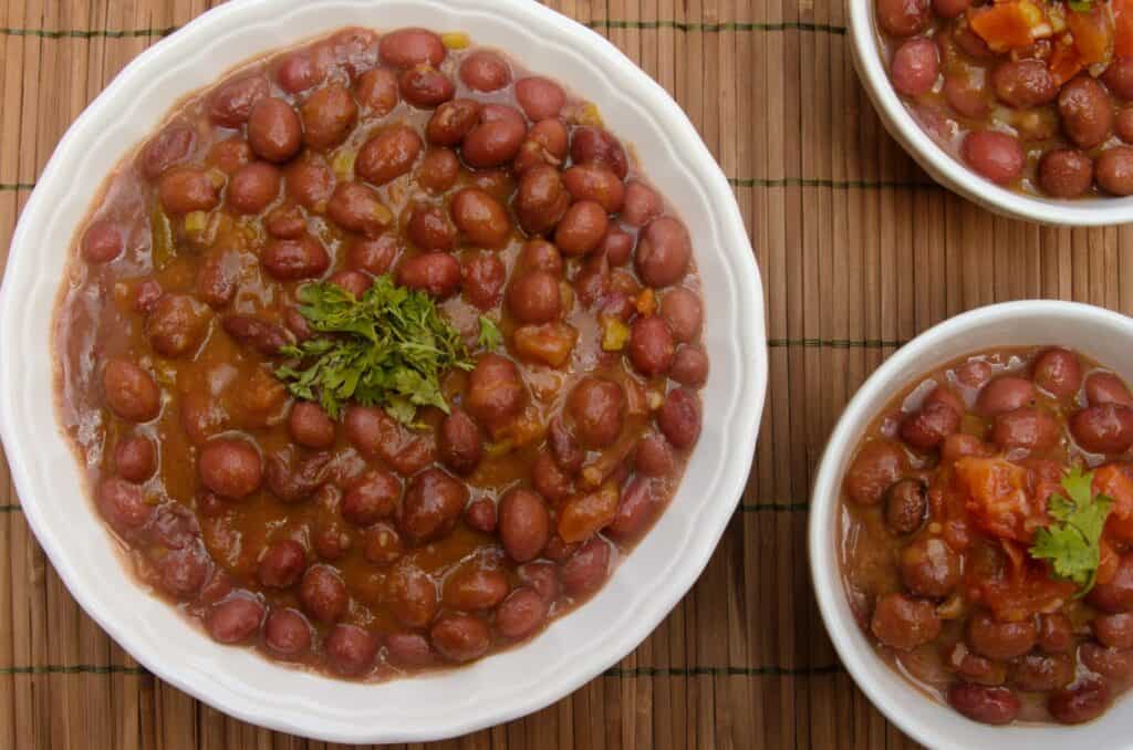 Three white bowls with red colombian beans in them on a table