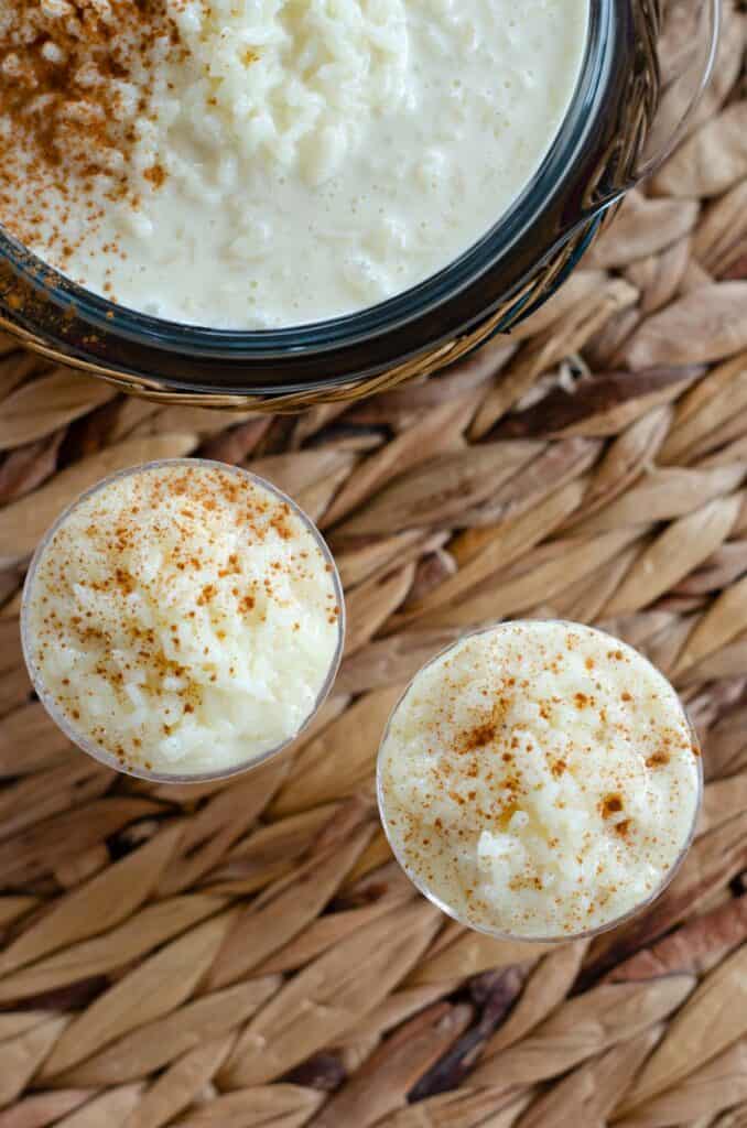 foto desde arriba de dos vasitos con arroz con leche colombiano y un bol grande de arroz con leche y canela