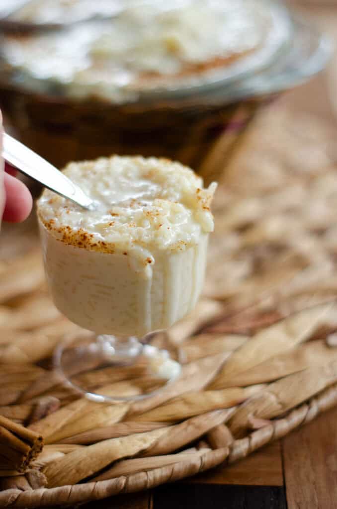 rice pudding oozing from the glass because a spoon is digging into the arroz con leche