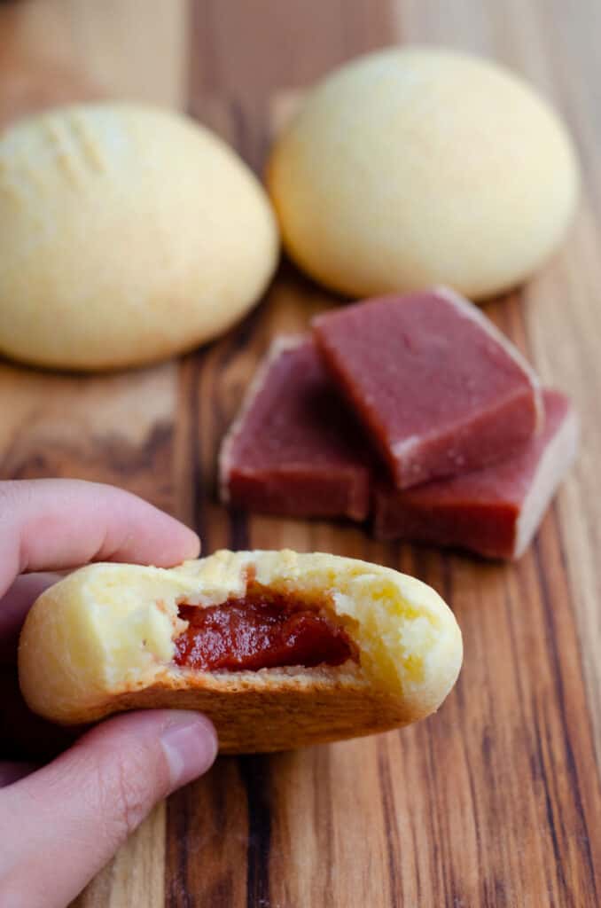 pandebonos with guava paste, showing the inside and showing blocks of bocadillo in the background