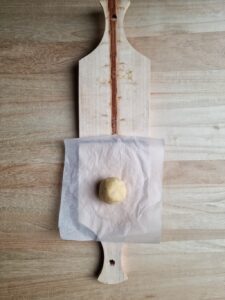 a ball of dough placed on the patacon press with nonstick paper