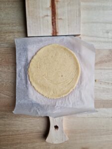 the flat circle of dough in the press to make the vegan empanada