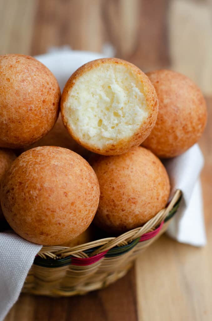 basket with bunuelos with one bunuelo with a bite out to show the inside
