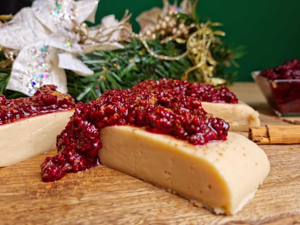 piezas de natilla colombiana con salsa de mora en una tabla de madera y decoracion de navidad