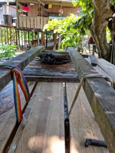 Black bag being pressed by a wooden press, tree and a house in the background