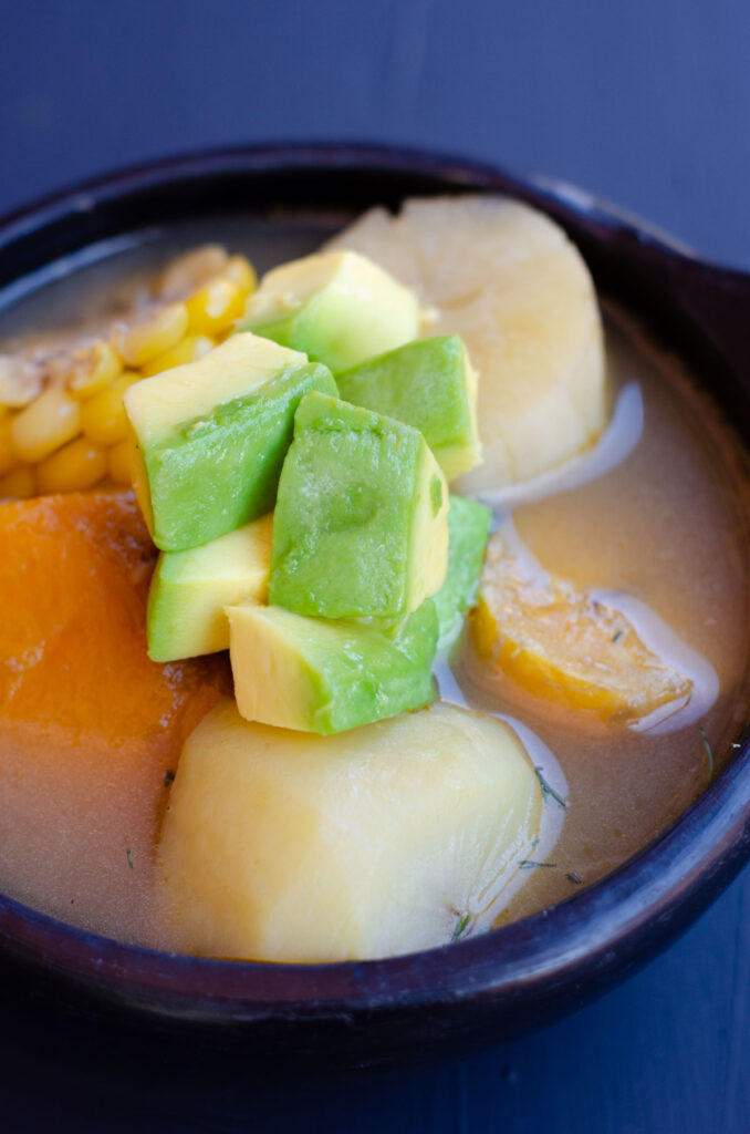 close up of a vegan sancocho topped wiith cubes of avocado