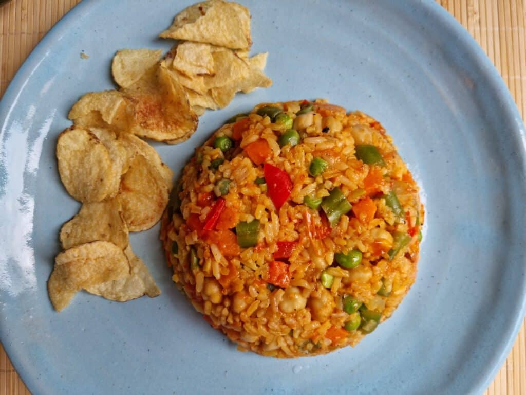 Blue plate with a dome of the rice with vegetables with a side of chips