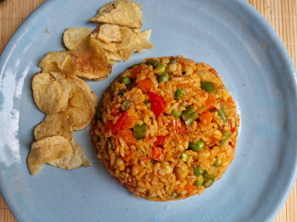 Plato azul con arroz de verduras y chips al lado