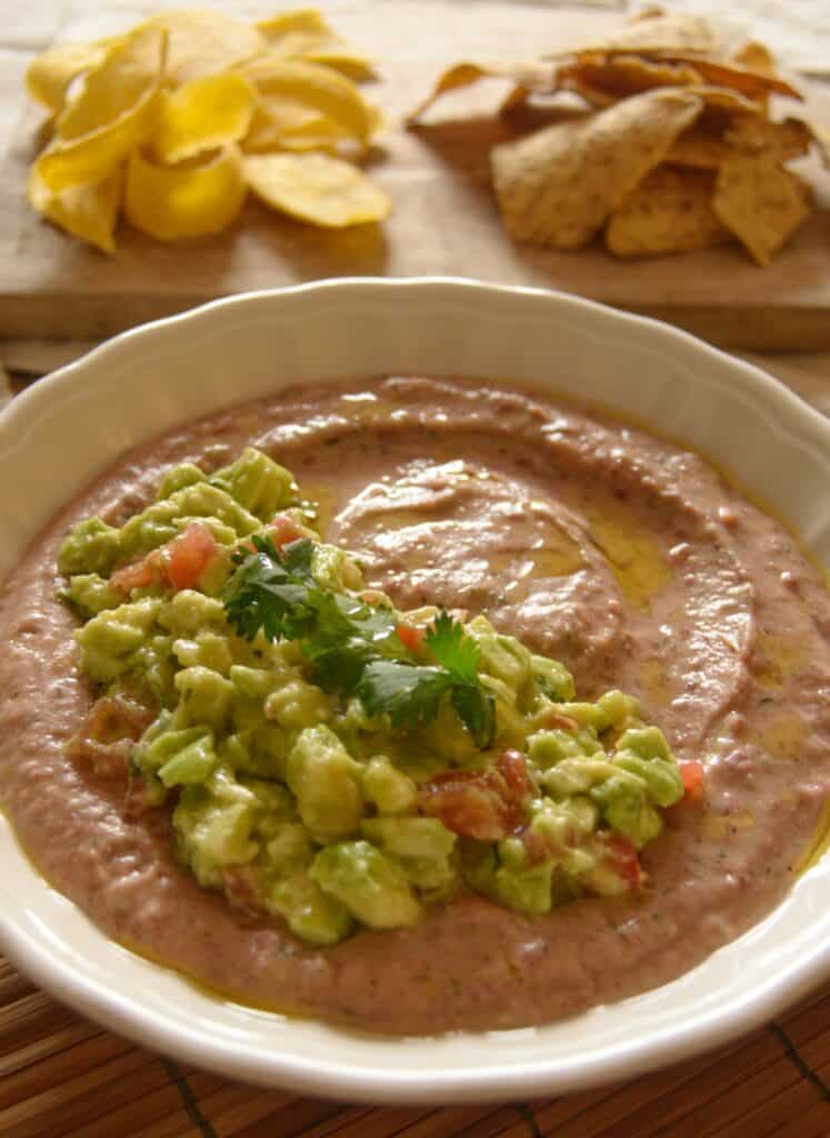 Dip de Frijoles con Salsa de Aguacate (Red Bean Dip with Avocado Salsa) in a bowl with chips to serve on a plate