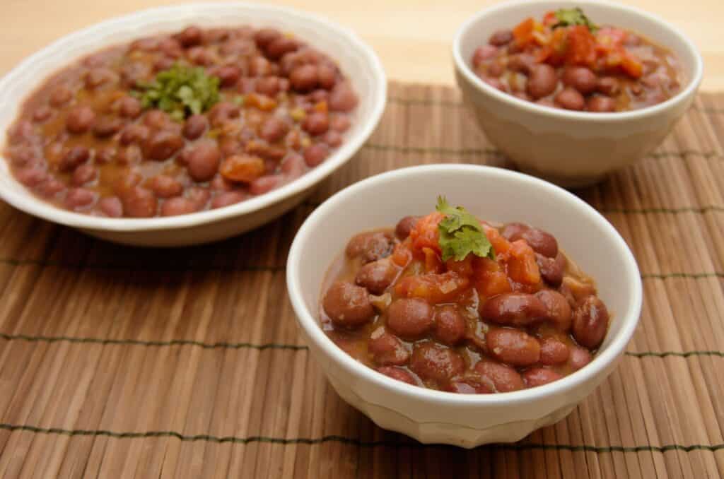 Three with bowls with creamy red beans or frijoles in them
