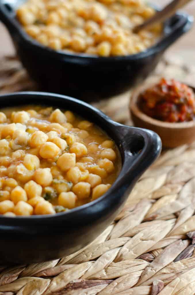 dos platos negros con garbanzos colombianos, uno tiene una cuchara