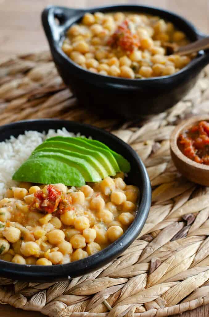 plato con garbanzos, arroz blanco y aguacate. al fondo es otro plato con solo garbanzos