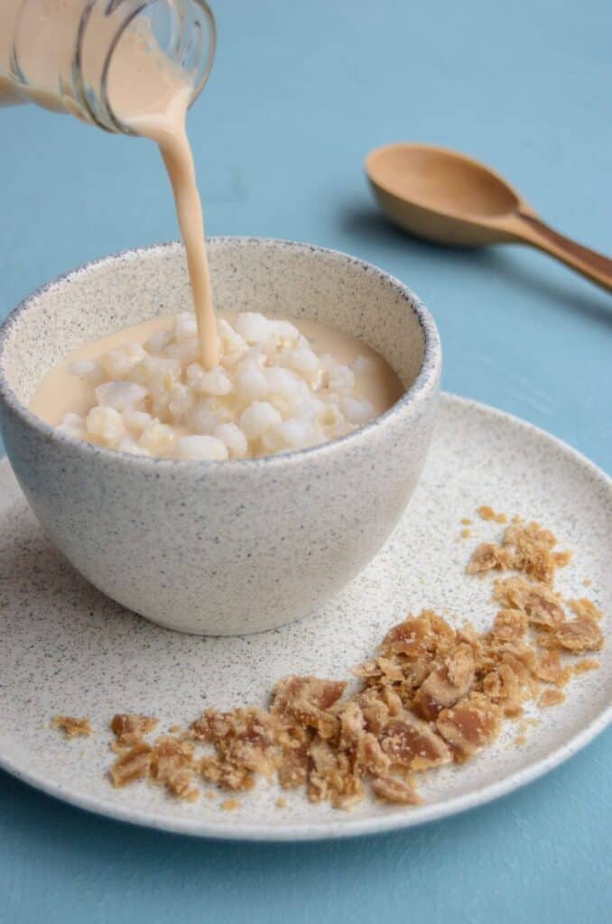 taza con maíz y la leche se vierte en la taza, con un platico con panela rallada