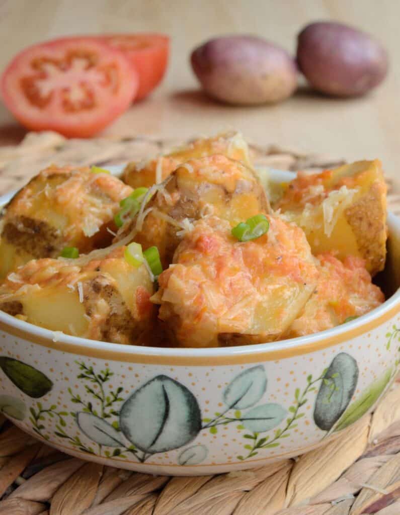 Bol colorido con papas chorreadas y papa y tomate al fondo