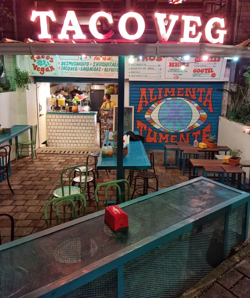 Terrace with blue furniture and kitchen of TacoVeg vegan restaurant in Medellin