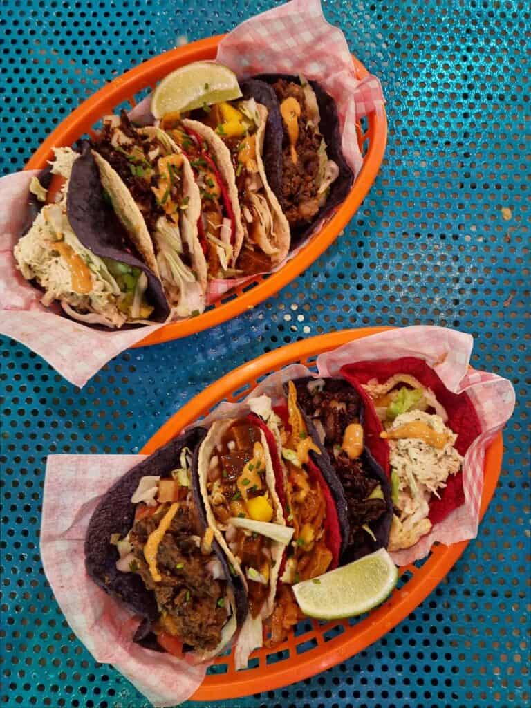 Two trays with 5 vegan tacos on a blue table