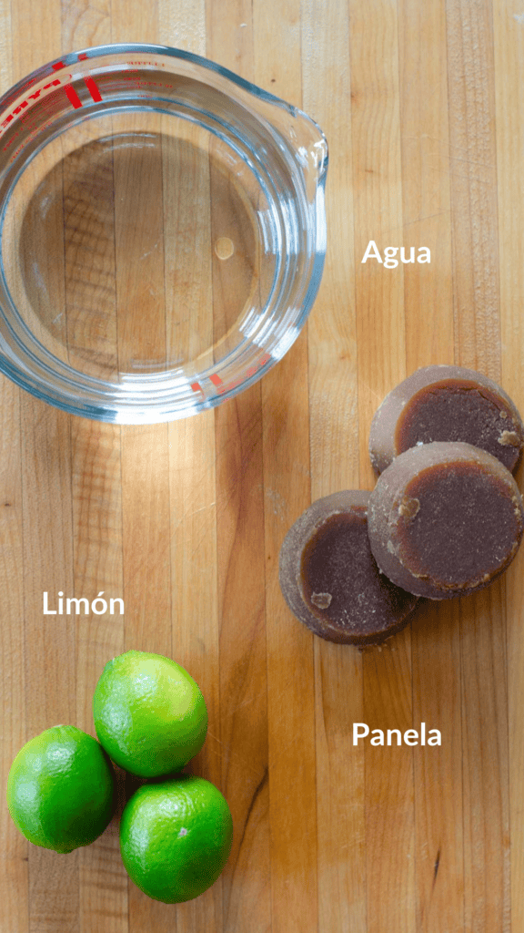 tabla de madera con los ingredientes: taza de agua, bloques de panela piloncillo y limones