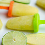 Green Mango Popsicles with slices of lime on a white plate