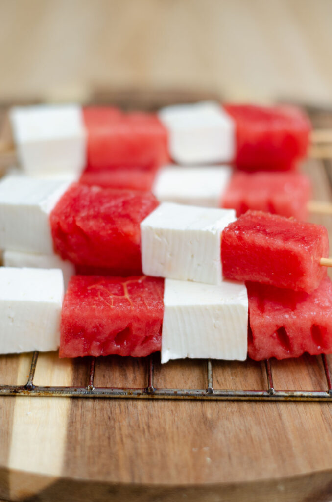 cheese and watermelon skewers before grilling on a wooden board