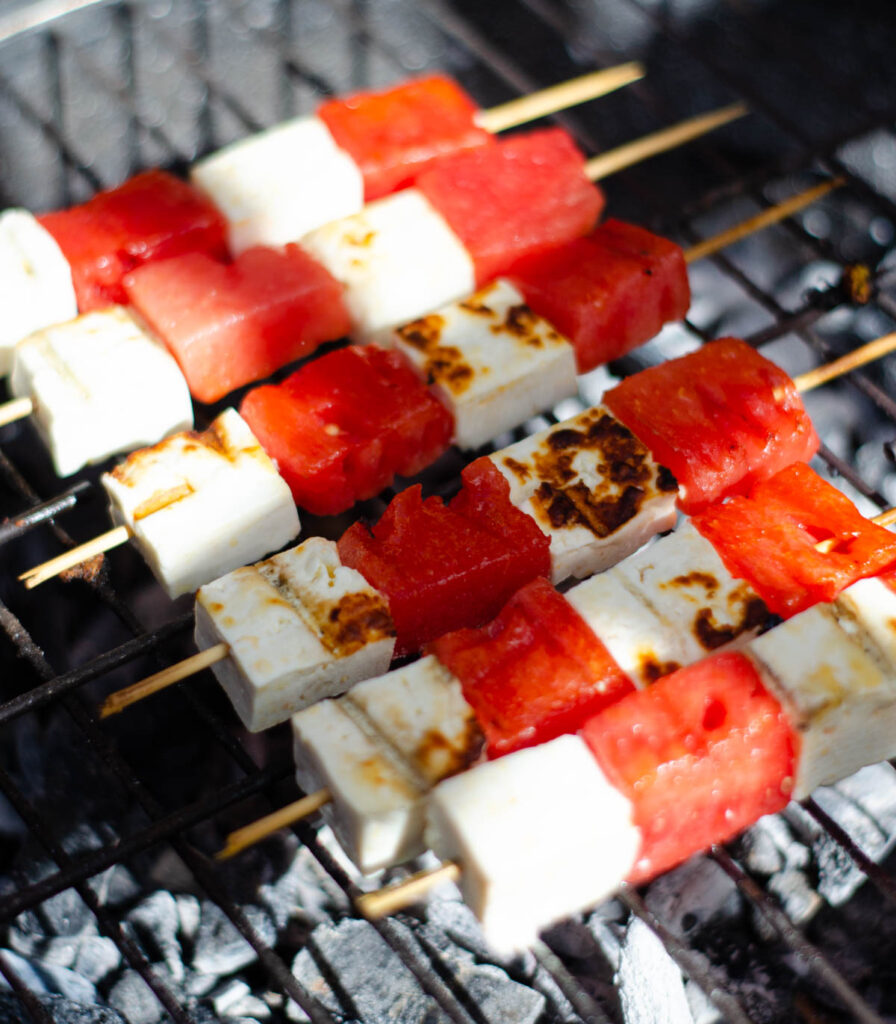 a couple of cheese and watermelon skewers on a BBQ grill