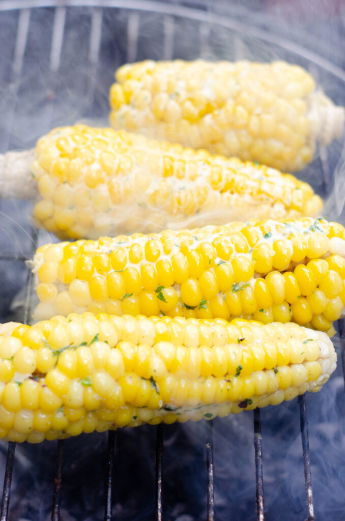 corn on the cob with melting garlic herb butter on the barbecue grill