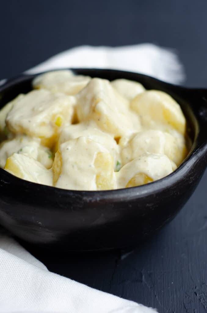 black bowl with boiled potatoes in cream sauce without fresh herbs on them