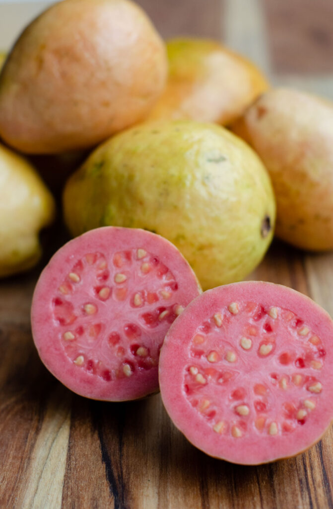 guava fruit with one guava sliced in halves to show the pink inside and the seeds