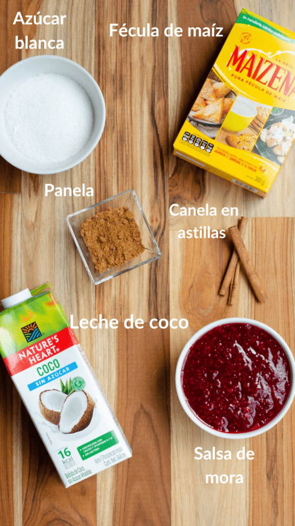 los ingredientes de la natilla en una tabla: azucar, maizena, panela, leche de coco, canela y salsa de mora