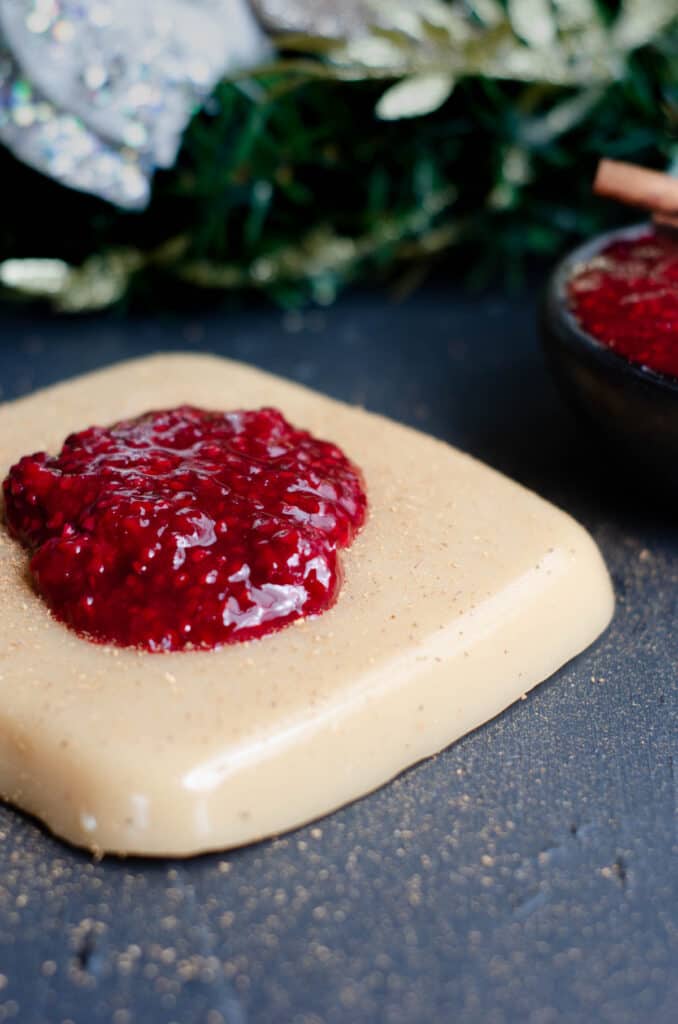 a vegan cornstarch pudding with blackberry sauce on a dark background with christmas decoration