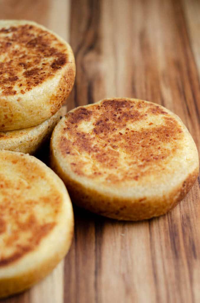 three golden brown arepas boyacences on a wooden board