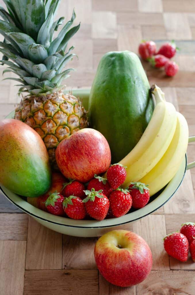 fruit basket with pineapple, papaya, mango, banana, apples and strawberries